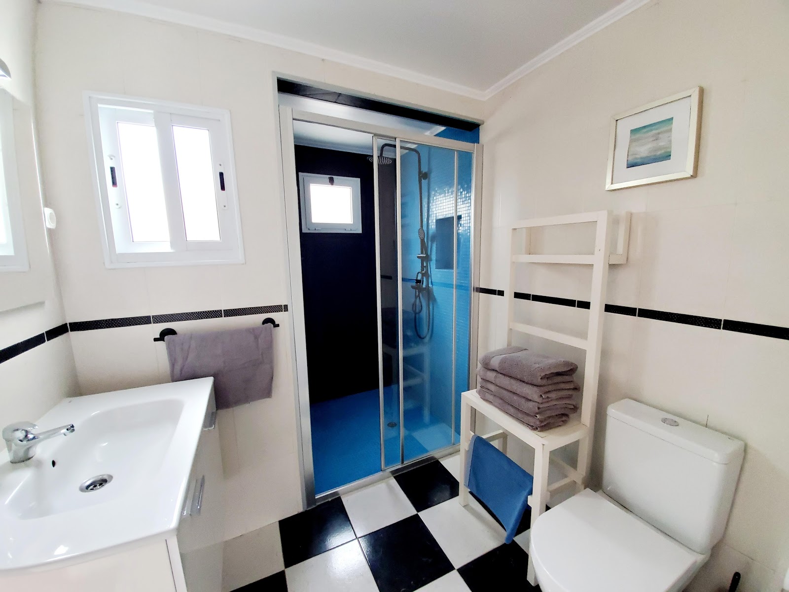 Bathroom with walk-in shower, sink, towels, and black-and-white tile floor