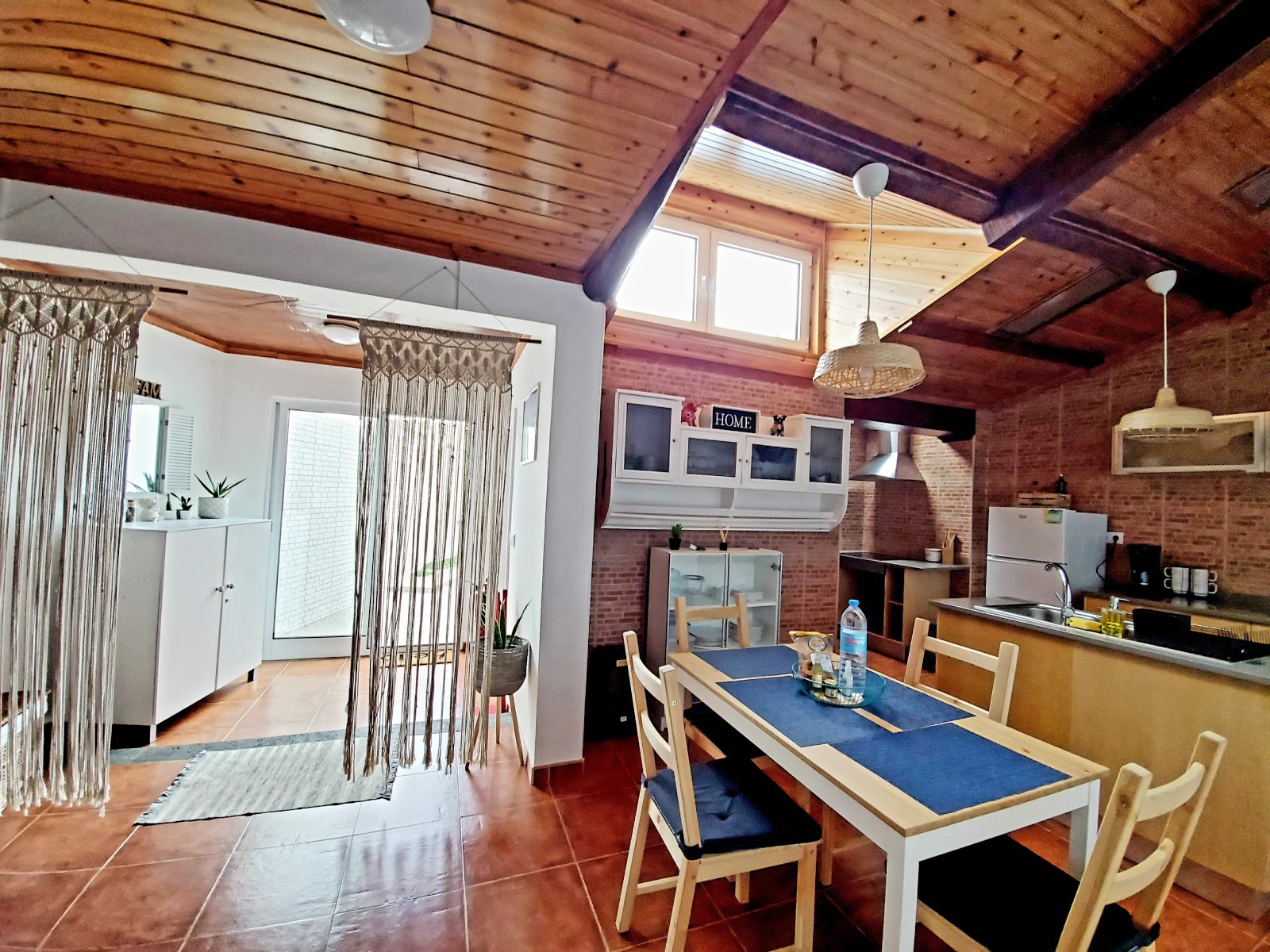 Bedroom with terracotta tile floor, wood ceiling, and coastal-style decor